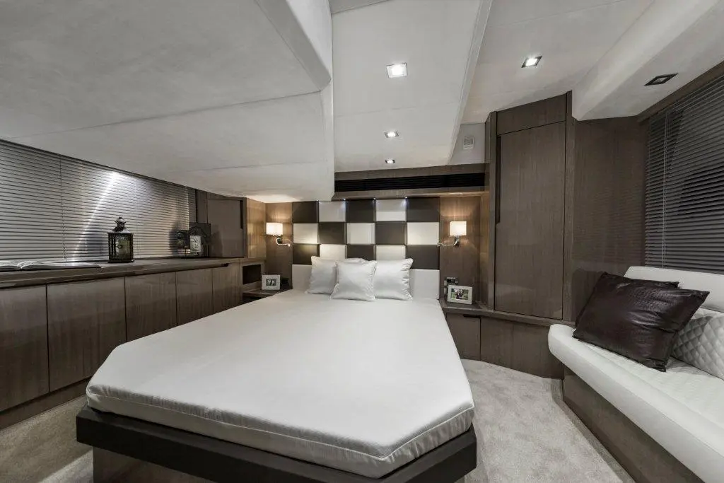Modern yacht bedroom with a king-sized bed, checkered wall decor, soft lighting, and stylish wooden furniture.