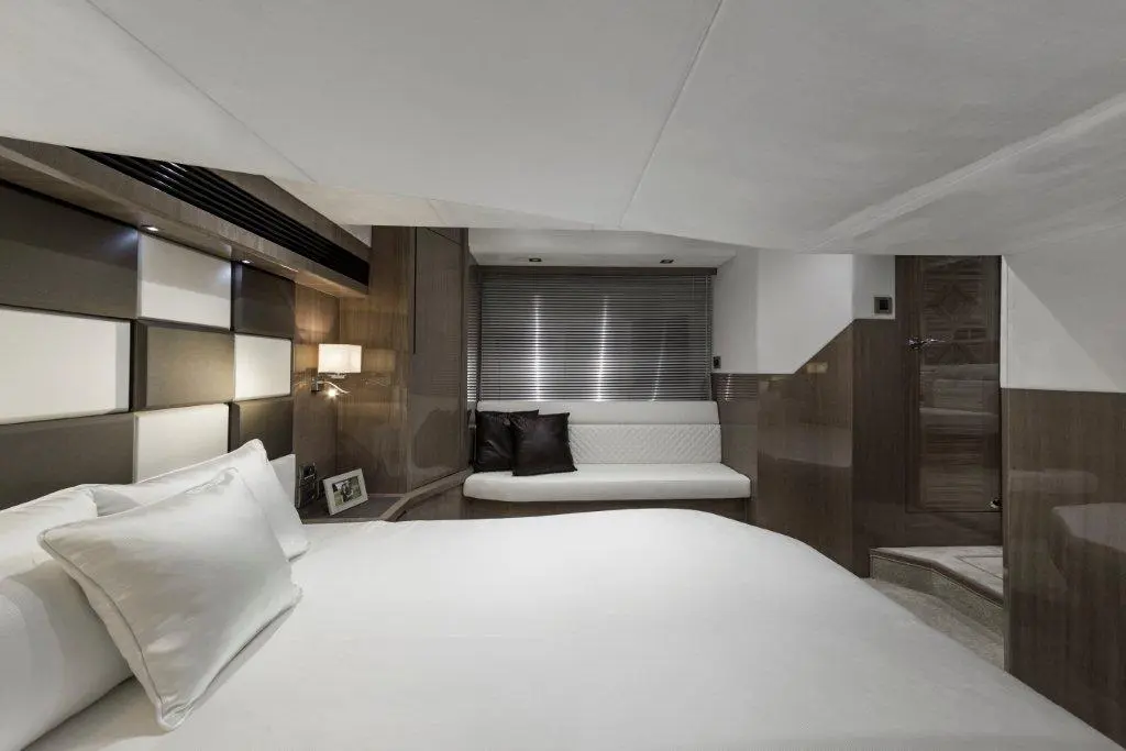 Modern bedroom with a large bed, stylish decor, and a cozy seating area, featuring soft lighting and neutral colors.