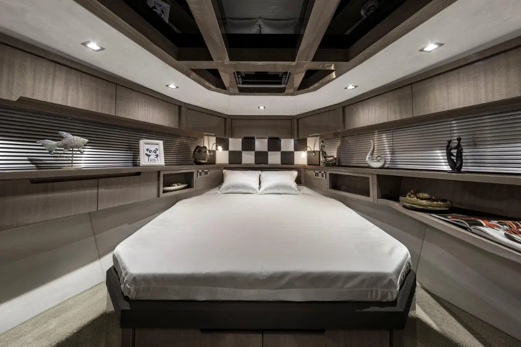 Modern yacht bedroom with a centralized bed, wooden panels, decorative items, and soft lighting.