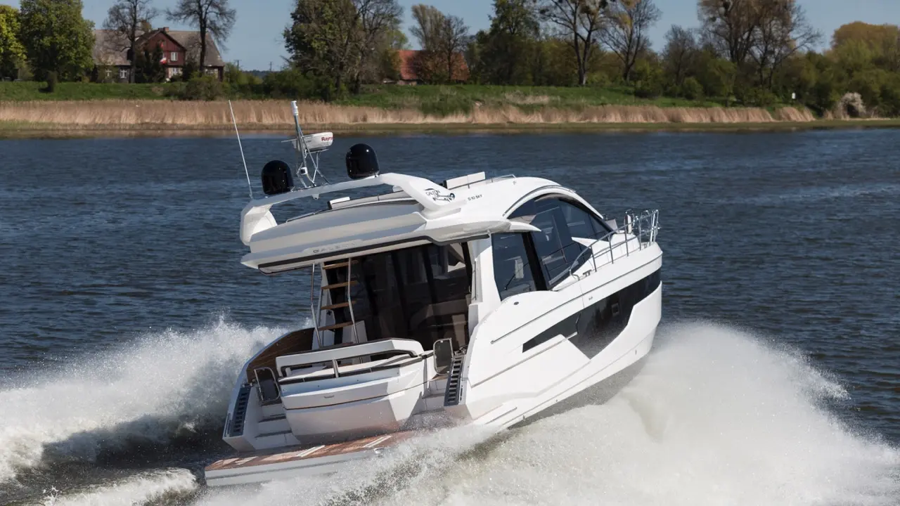 A sleek white motorboat cuts through gentle waves on a river, showcasing its modern design against lush greenery.