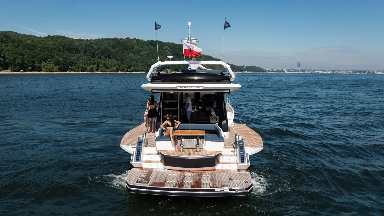 Luxury yacht 'Galeon' cruising on calm waters, featuring two women relaxing on the deck and a Polish flag flying above.