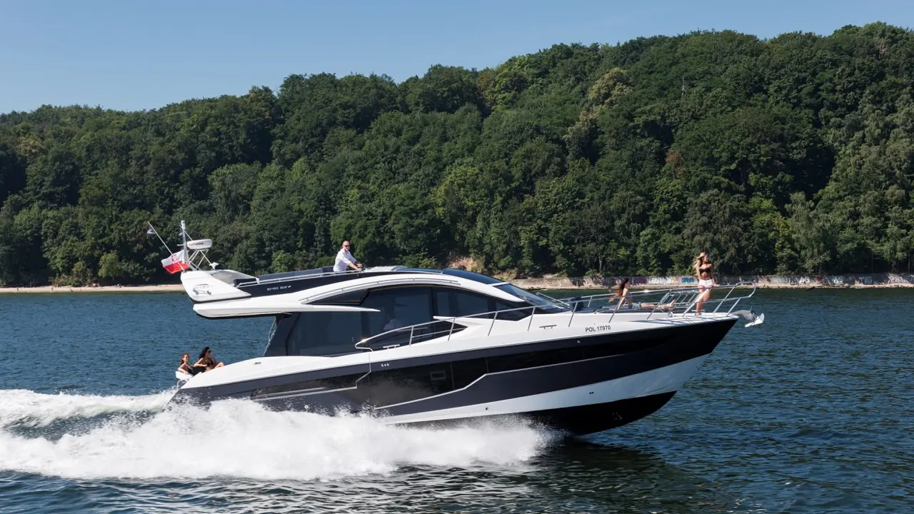 A sleek black and white motorboat with passengers cruising on water, surrounded by lush greenery and a sandy shore.