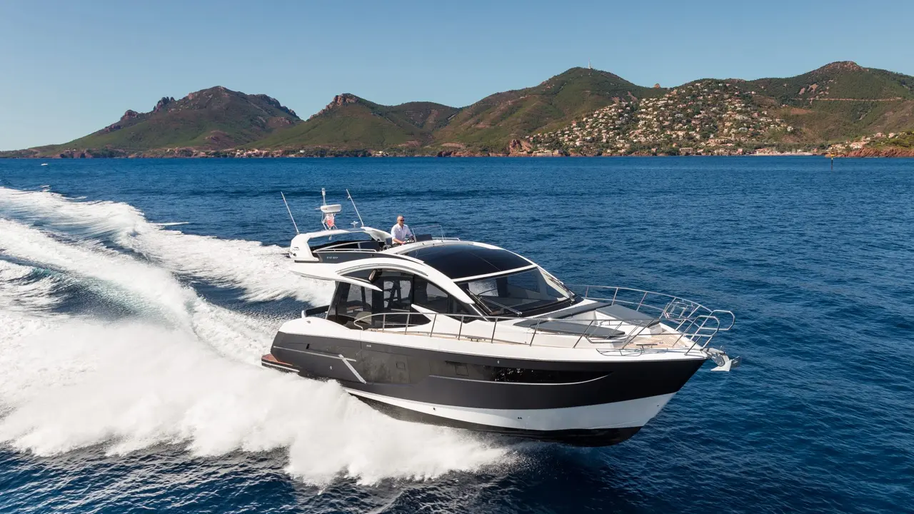 A sleek motorboat speeds across blue waters with mountains in the background, showcasing luxury and adventure on the sea.