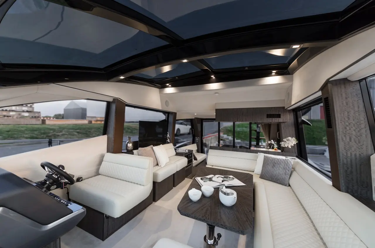 Luxury yacht interior featuring modern furniture, large windows, and a coffee table with decorative items.