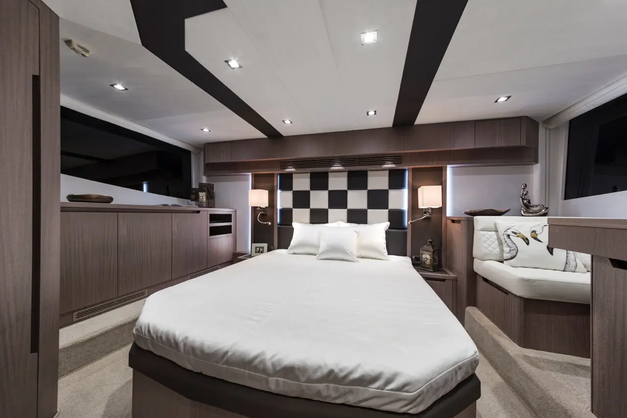 Modern yacht bedroom featuring a queen bed, checkered accent wall, ambient lighting, and stylish seating area.