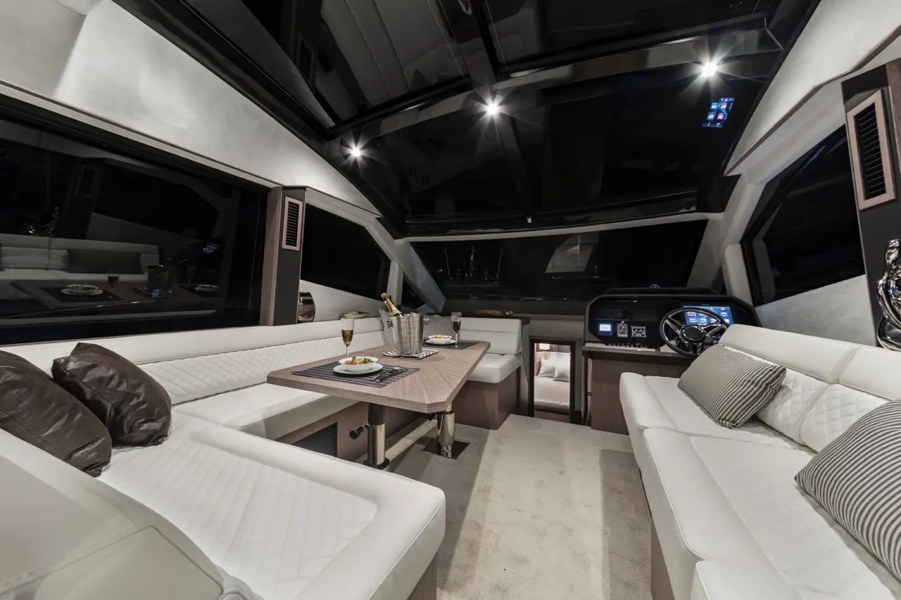 Luxurious boat interior featuring modern seating, a dining table with plates, drinks, and a sleek control panel.