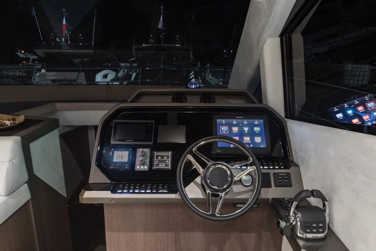 View of a modern boat's control panel featuring screens, a steering wheel, and a digital display showing 316° navigation.
