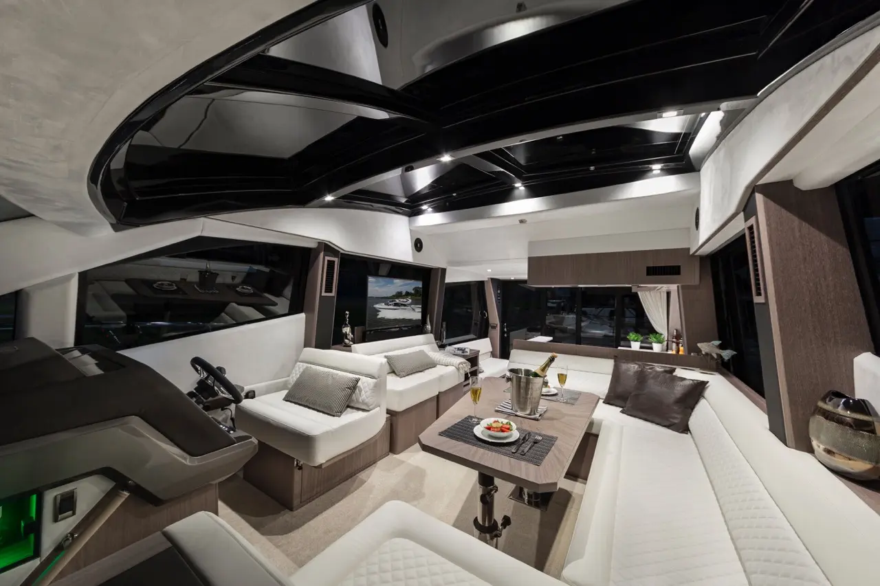 Luxurious yacht interior featuring modern seating, dining table, and panoramic windows with views of water, ideal for relaxation.