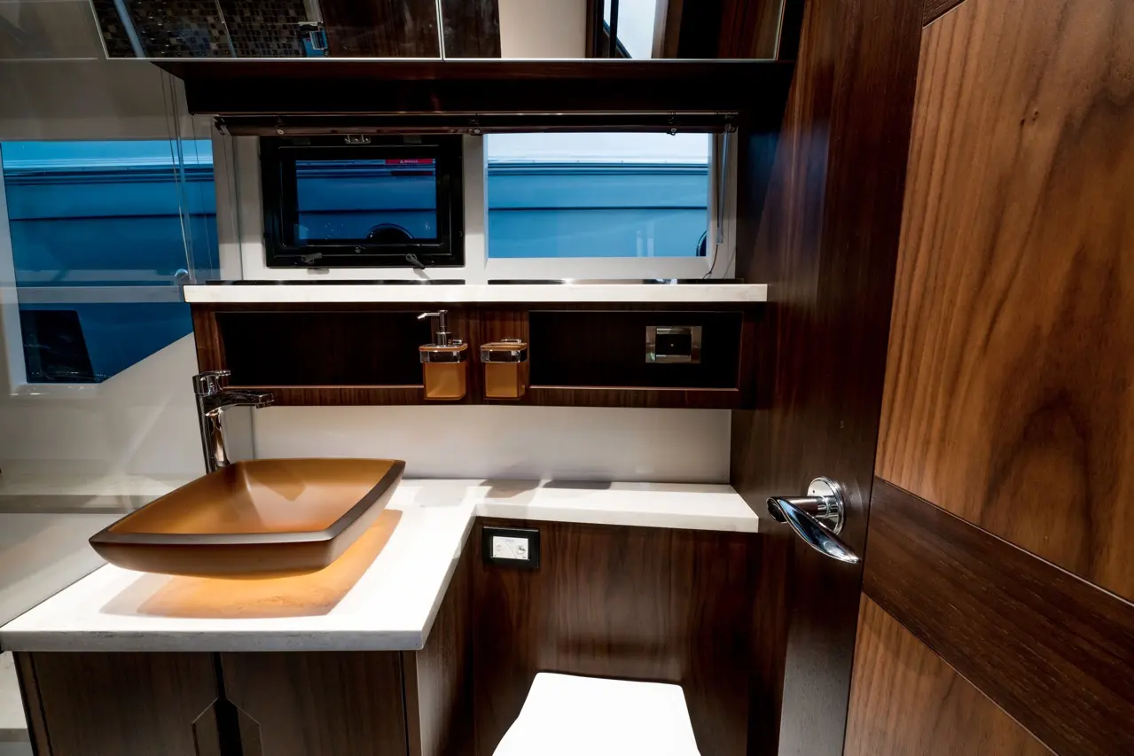 Luxury bathroom featuring a brown bowl sink, modern faucet, and wood cabinetry with a mirror and window above.