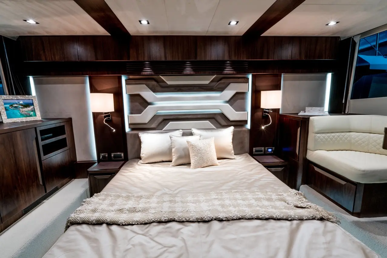 Luxurious bedroom with a large bed, decorative pillows, ambient lighting, and a sleek wall design, featuring a picture frame.