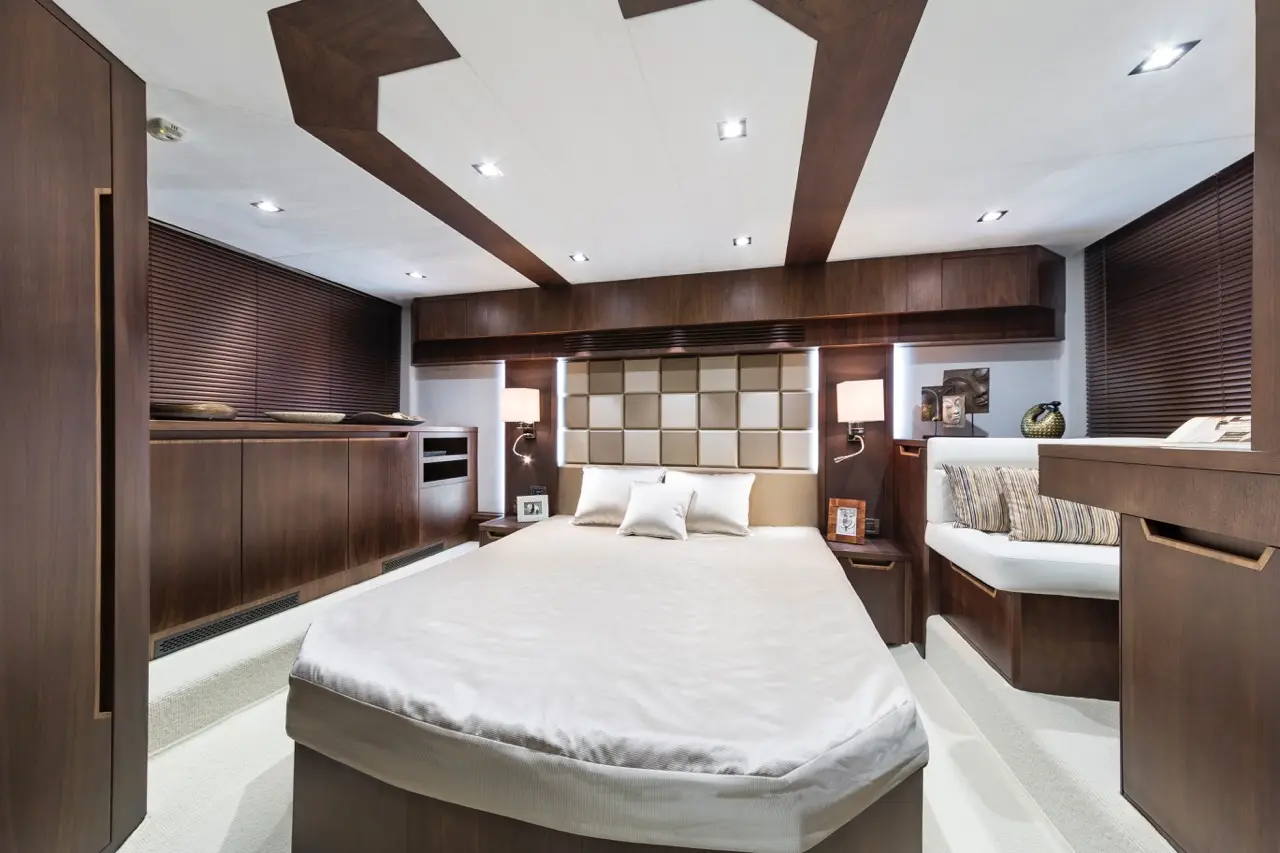 Modern bedroom with a double bed, wooden accents, bedside lamps, and decorative cushions against a stylish headboard.