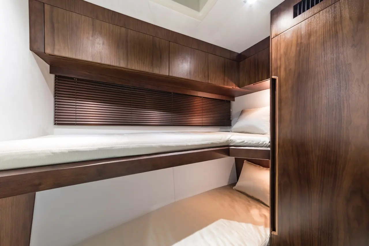 Cozy cabin interior featuring two wooden bunk beds with white mattresses and blinds, ideal for space-saving sleeping arrangements.