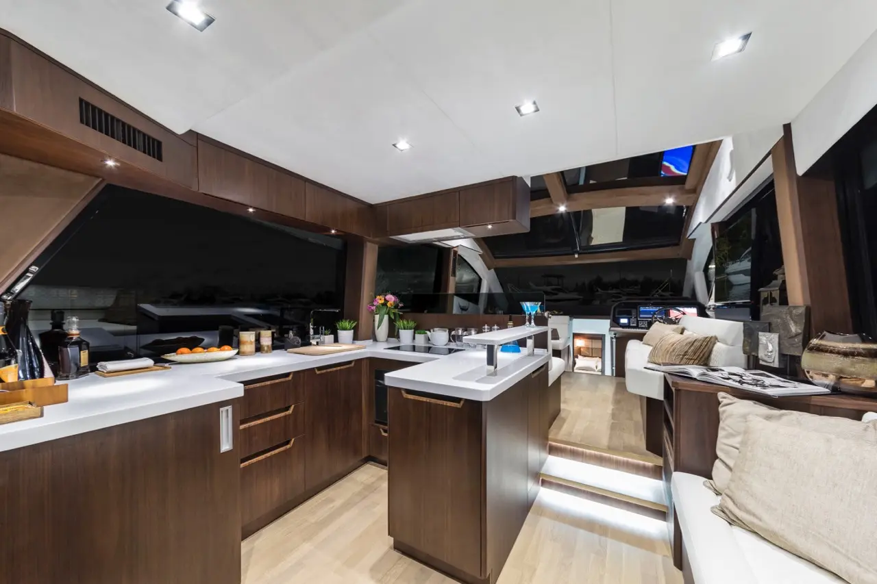 Modern yacht interior featuring a sleek kitchen, stylish cabinetry, and a cozy seating area, illuminated by soft lighting.