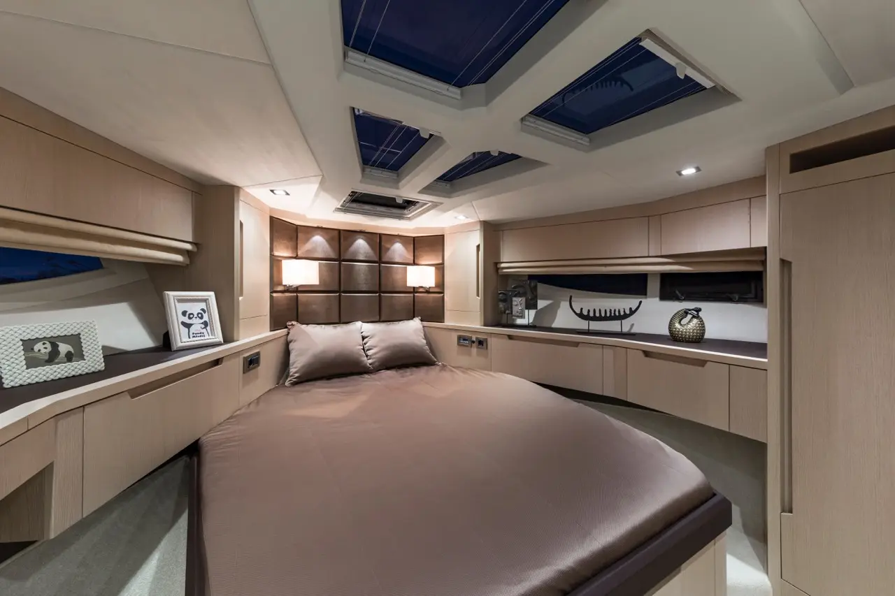 Cozy yacht bedroom featuring a large bed, stylish decor, and framed panda artwork under skylights and ambient lighting.