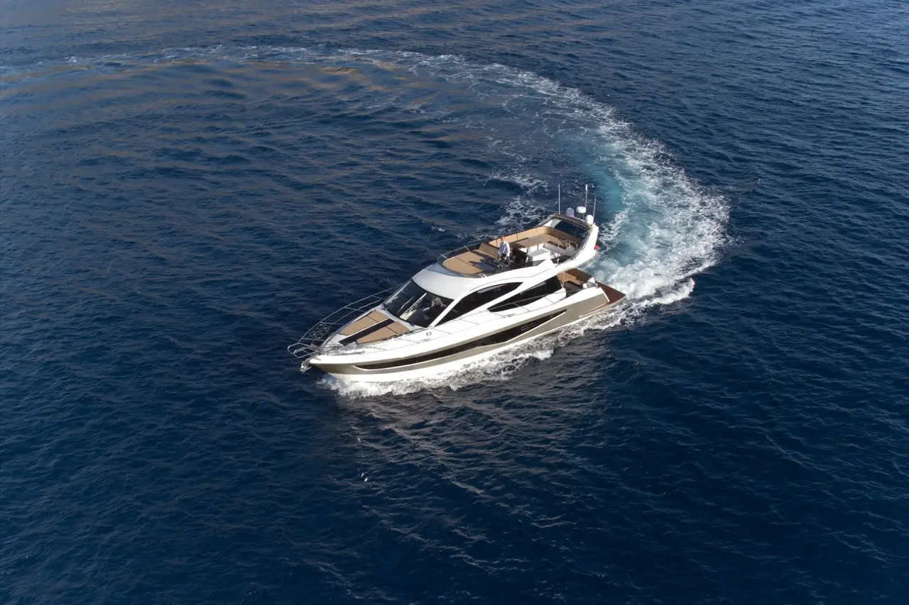Luxury yacht cruising through deep blue waters, leaving a wake behind as a captain navigates from the helm.