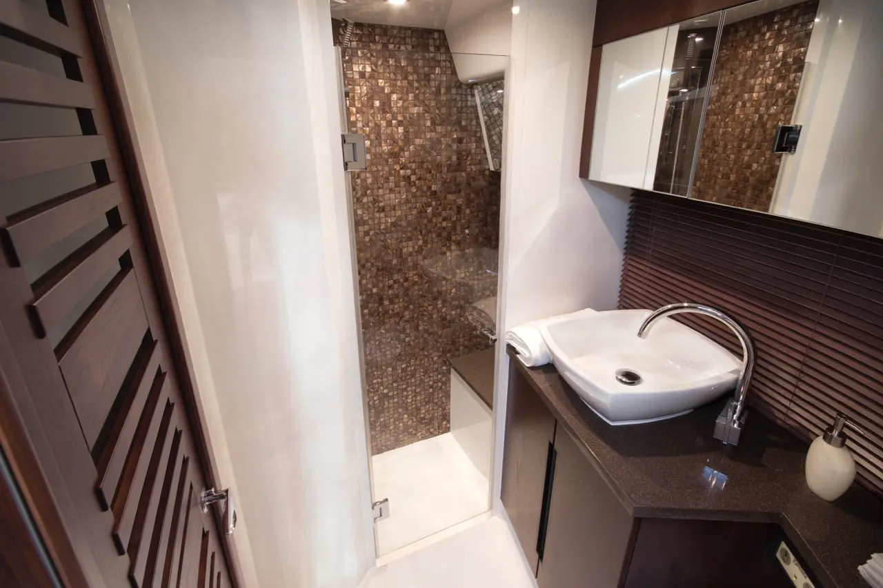 Modern bathroom featuring a walk-in shower with mosaic tiles, a sleek sink, and stylish wooden accents.
