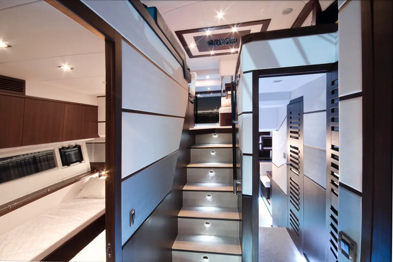 Sleek yacht interior featuring a stairway with LED lights, leading to a cozy sleeping area and modern cabinetry.