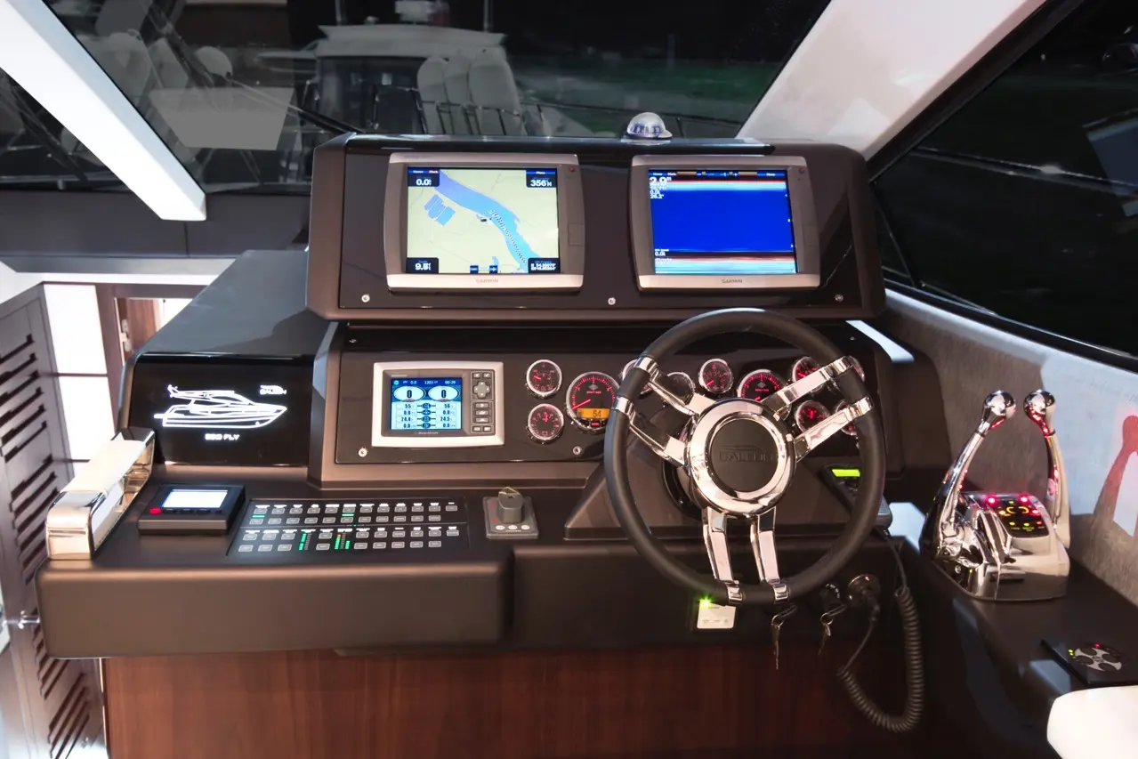 Modern yacht dashboard featuring two Garmin screens, navigation controls, a sleek steering wheel, and digital gauges.
