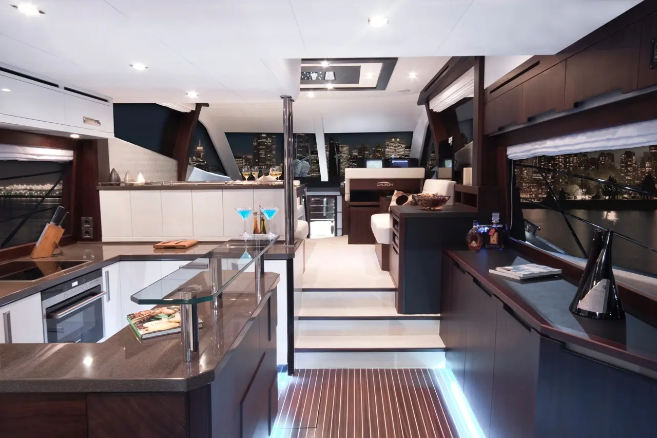 Modern yacht interior with a sleek kitchen, lounge area, city skyline view, and cocktails on the table. Elegant decor and lighting.