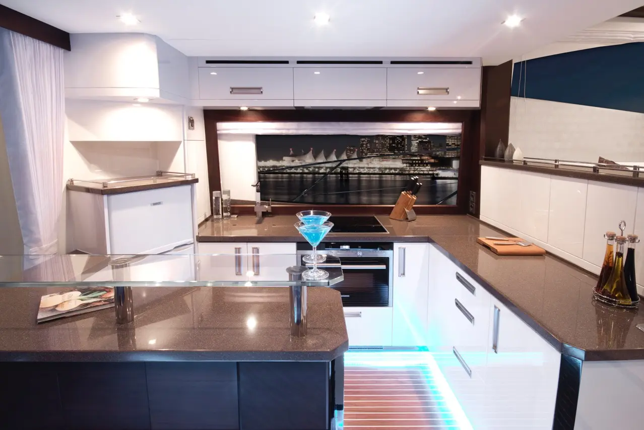 Modern kitchen with sleek cabinetry, a blue cocktail on the counter, and a cityscape view in the background.