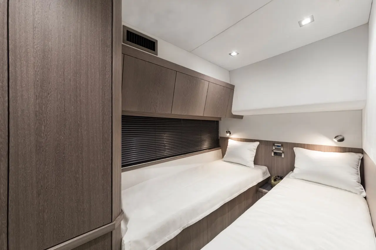 Two single beds with white linens in a modern, minimalistic room featuring wooden accents and built-in storage.