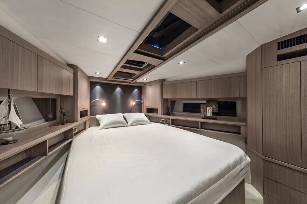 Modern yacht bedroom with a large bed, wooden cabinetry, decorative items, and soft lighting.