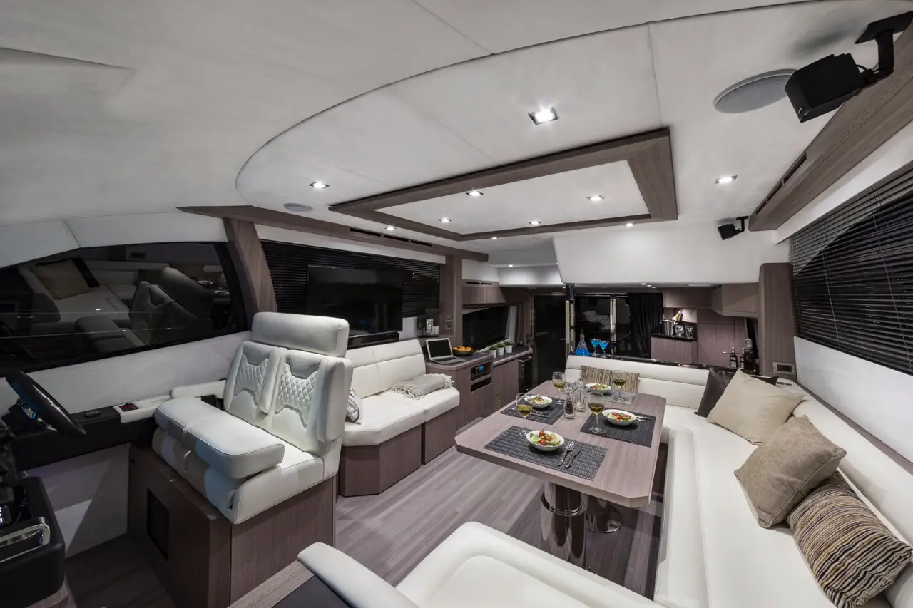 Modern yacht interior featuring a dining area with salad plates, plush seating, and a sleek control station.