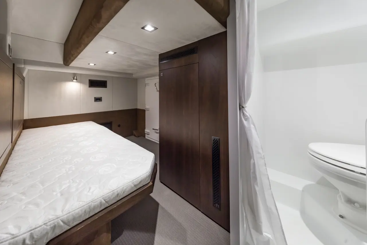 Modern bedroom with a mattress, wooden storage cabinet, and a bathroom area with a toilet behind a white curtain.