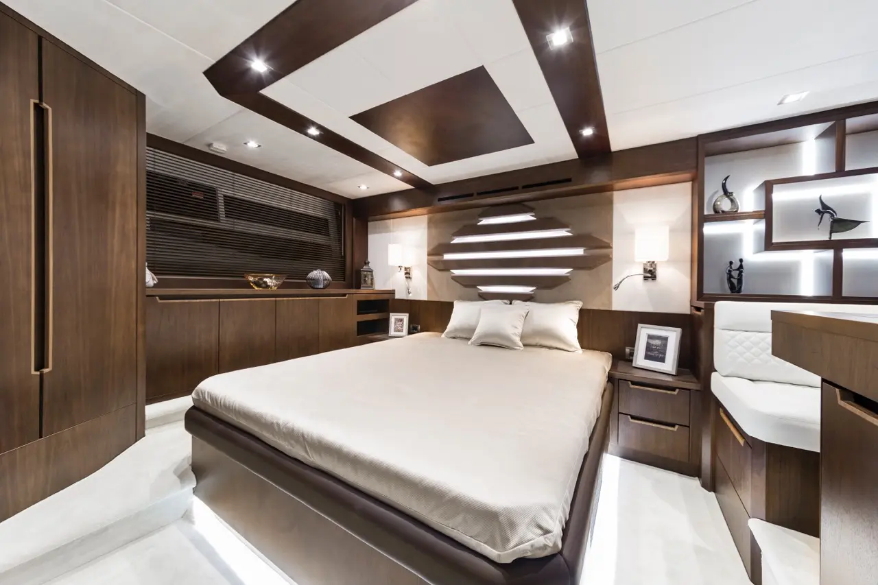 Luxurious bedroom in a yacht featuring a queen bed, wood paneling, modern lighting, and decorative accents.
