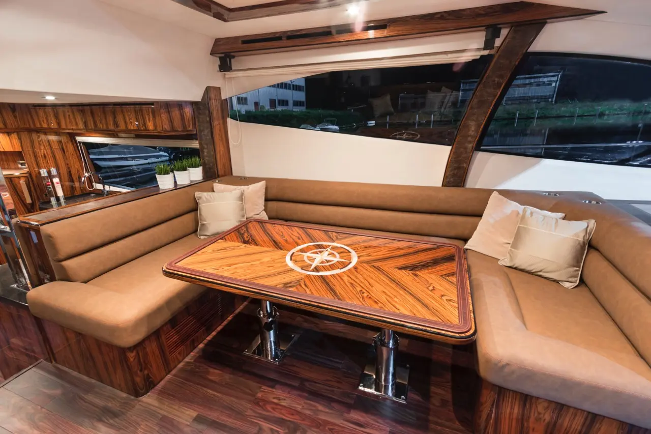 Luxurious yacht interior featuring a wooden table with compass design, leather seating, and large windows with a view.