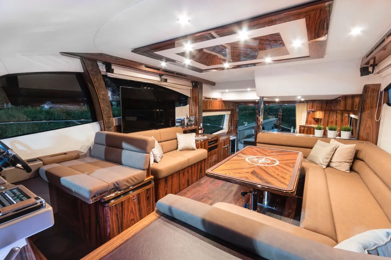 Interior of a luxury yacht featuring a spacious lounge area, modern furnishings, wooden accents, and a central dining table.