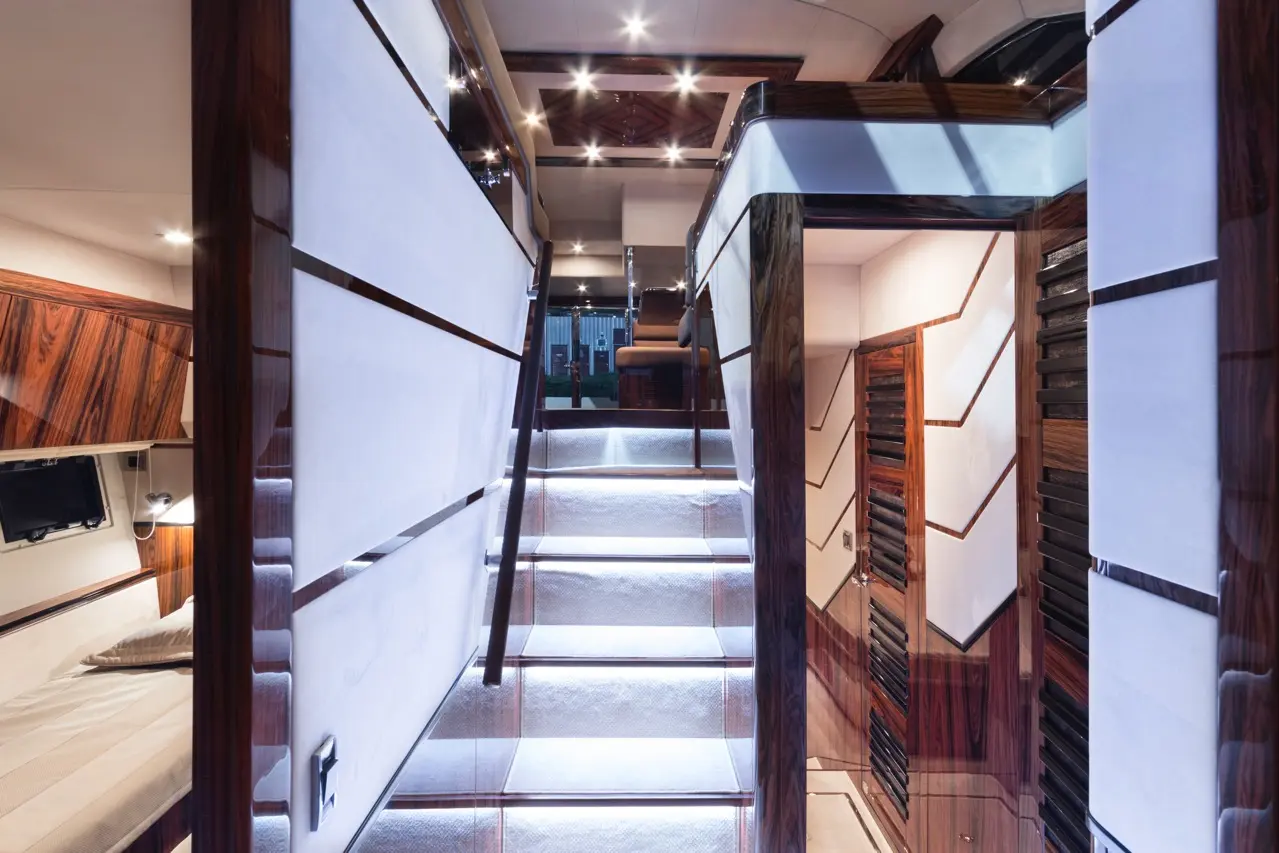 Luxurious yacht interior featuring polished wood, illuminated stairs, and modern design elements leading to upper levels.