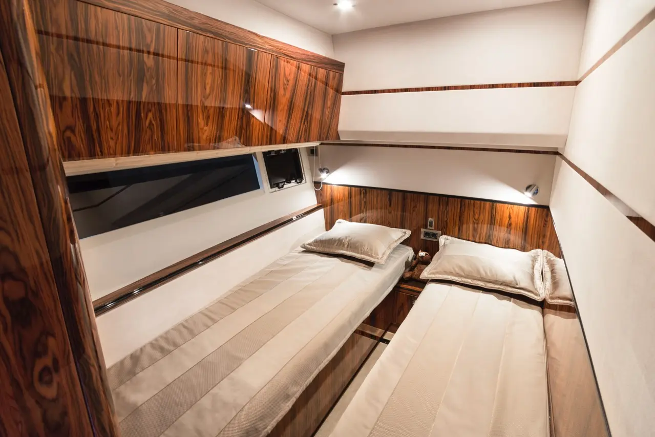 Elegant modern bedroom with twin beds, wood paneling, and ambient lighting. Features decorative pillows and a small teddy bear.