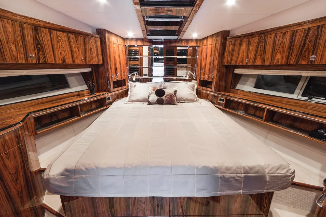 Luxurious yacht cabin with a large bed, wooden cabinetry, stylish decor, and soft lighting for an elegant ambiance.