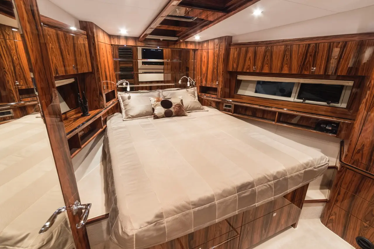 Luxurious yacht bedroom features a queen bed with plush bedding, wooden cabinetry, and stylish decor. Ideal for relaxation.