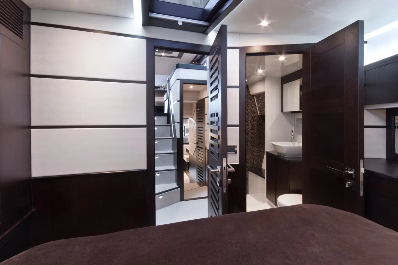Luxurious interior of a yacht cabin featuring wooden doors, modern staircase, and an elegant bathroom sink area.