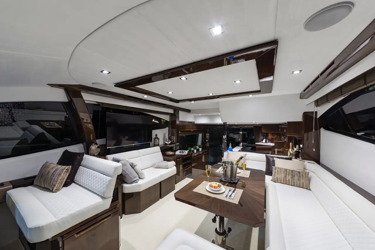 Luxurious yacht interior featuring a modern lounge with white sofas, a wooden dining table, and elegant décor.