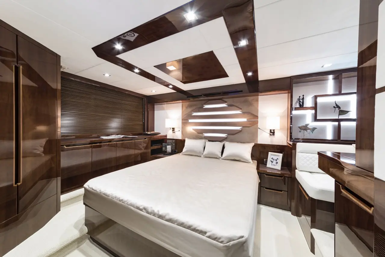 Luxurious yacht bedroom featuring a king-sized bed, wooden decor, ambient lighting, and stylish shelves with decor items.