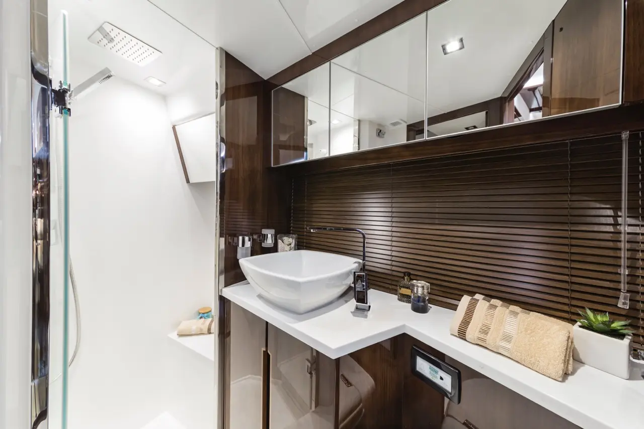 Modern bathroom features a white vessel sink, dark wood cabinetry, and a glass shower, with towels and decorative items.