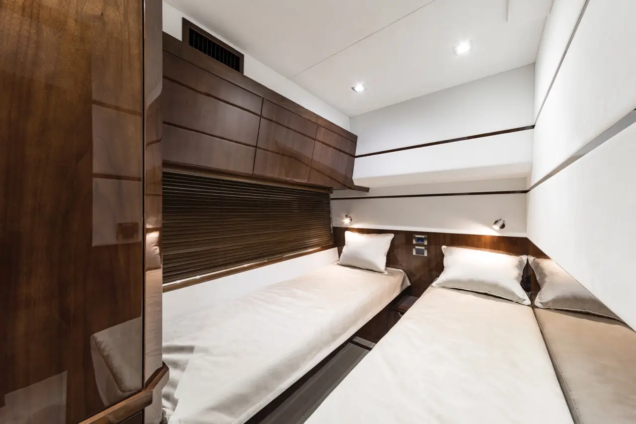 Modern twin bedroom featuring wood panels, two beds with plush pillows, and built-in cabinetry. Soft lighting enhances the space.
