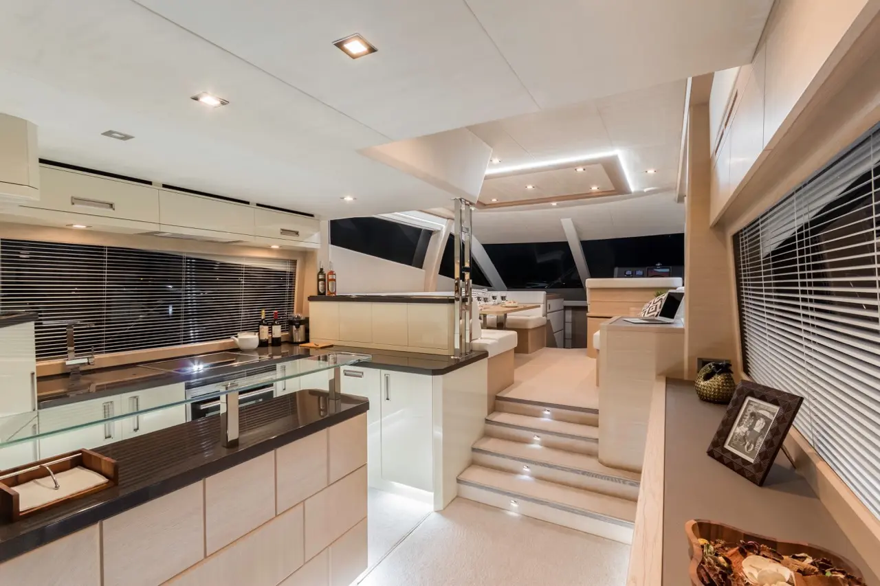 Modern yacht interior showcasing a sleek kitchen with glass elements, elegant seating area, and ambient lighting.