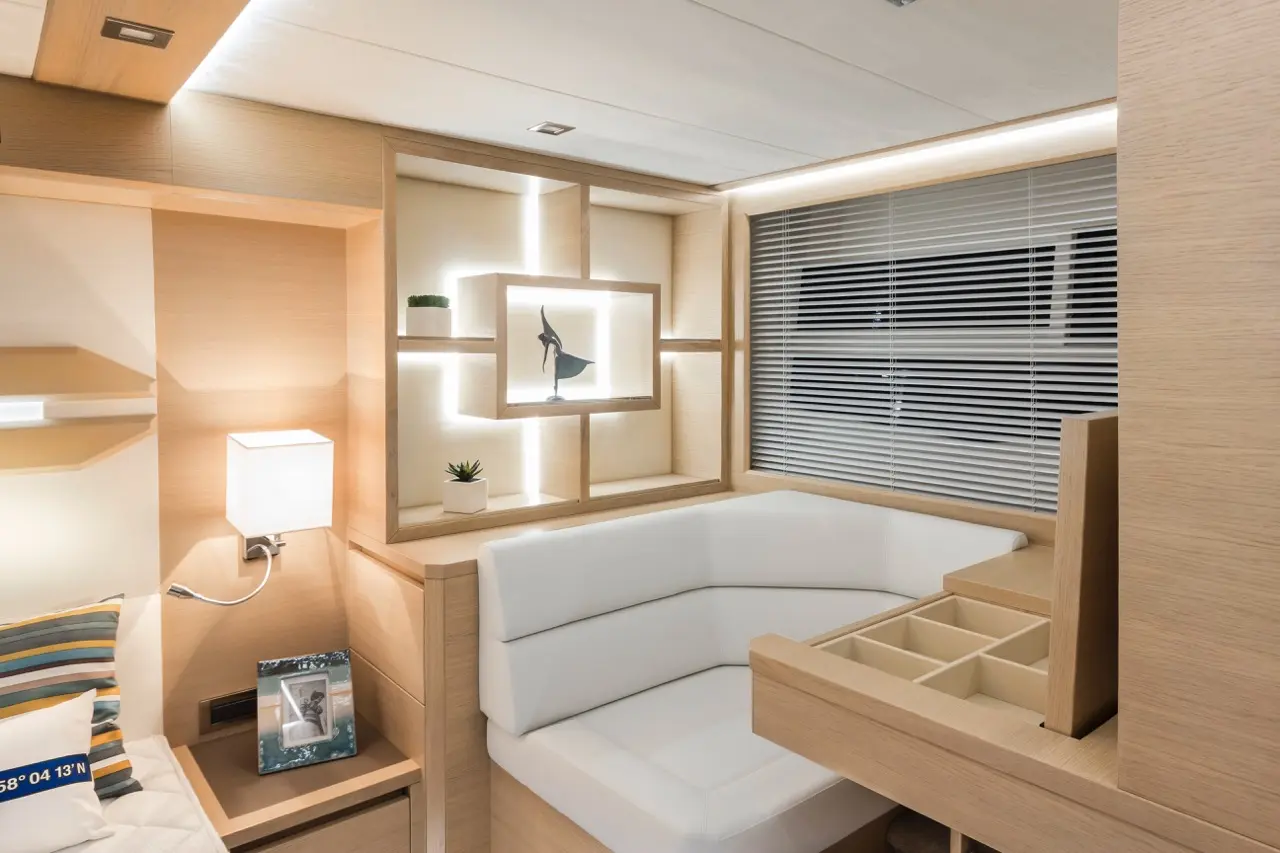 Modern interior with a white couch, nightstand, decorative shelving, and ambient lighting in a cozy room setting.