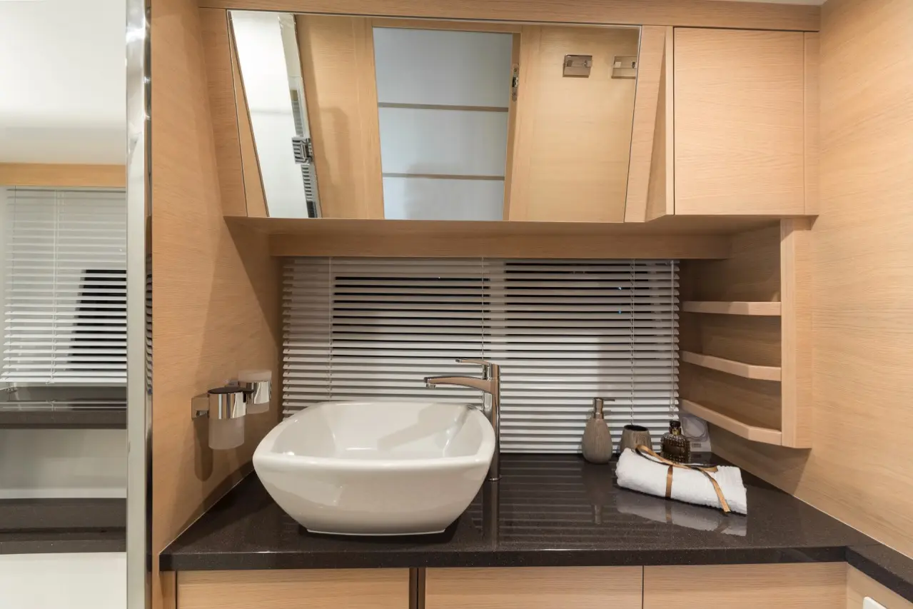 Modern bathroom featuring a white vessel sink, chrome faucet, wooden cabinetry, and a mirror above with horizontal blinds.