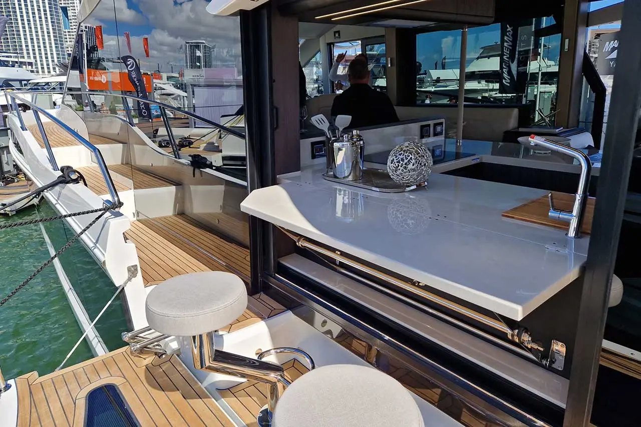 Luxury yacht cockpit featuring modern seating, marble countertop, and outdoor kitchen area overlooking the water.