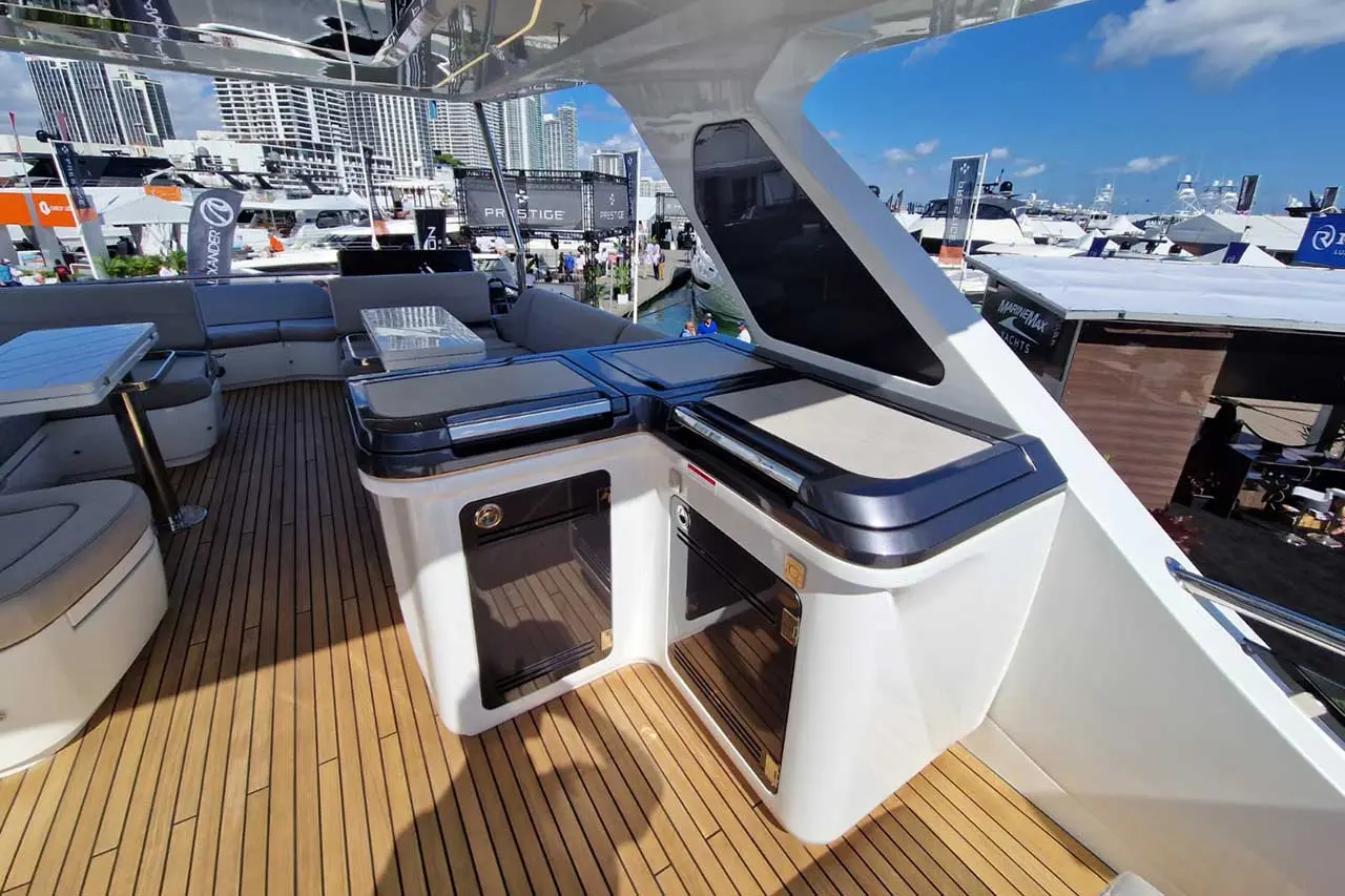Luxury yacht deck with teak flooring, built-in storage, and sleek seating, showcasing marina views under a clear blue sky.