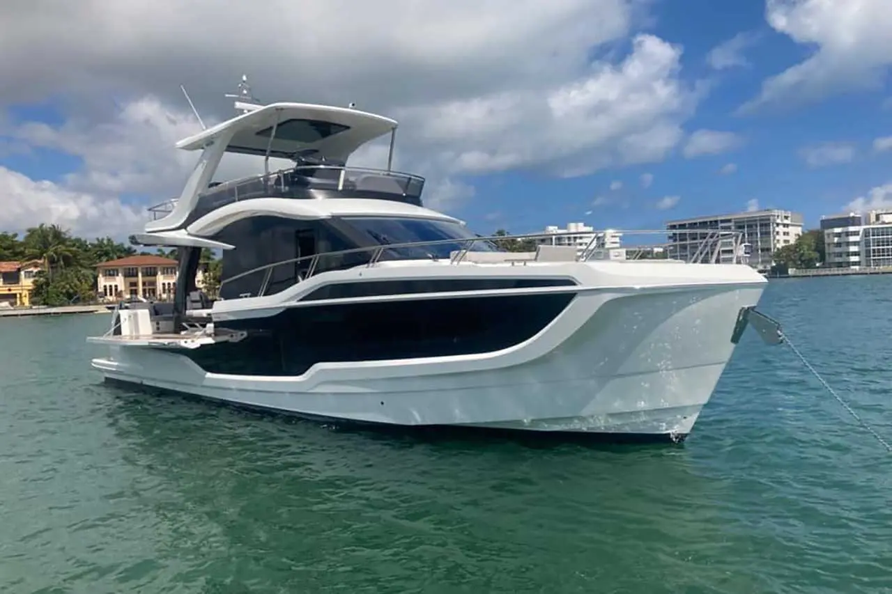 Luxury yacht docked in turquoise waters, showcasing modern design and nearby waterfront properties under a blue sky.