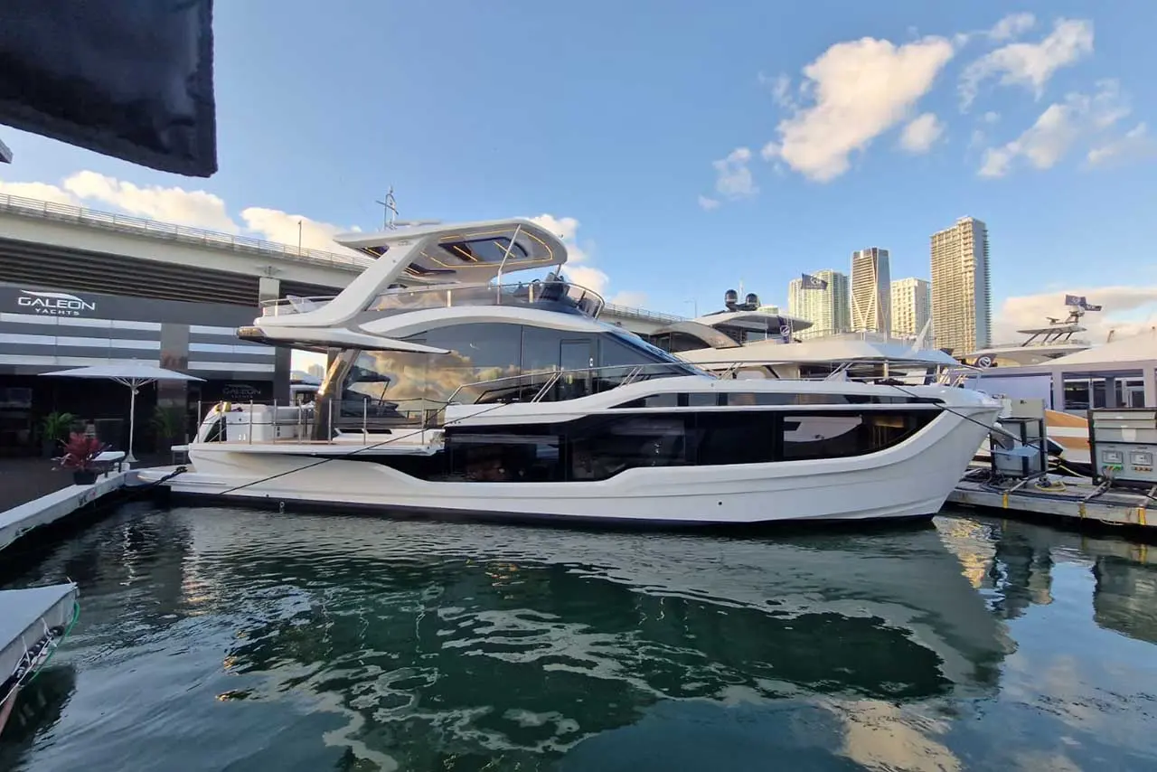 Luxury yacht docked at Galeon Yachts, surrounded by water and city skyline under a clear blue sky.