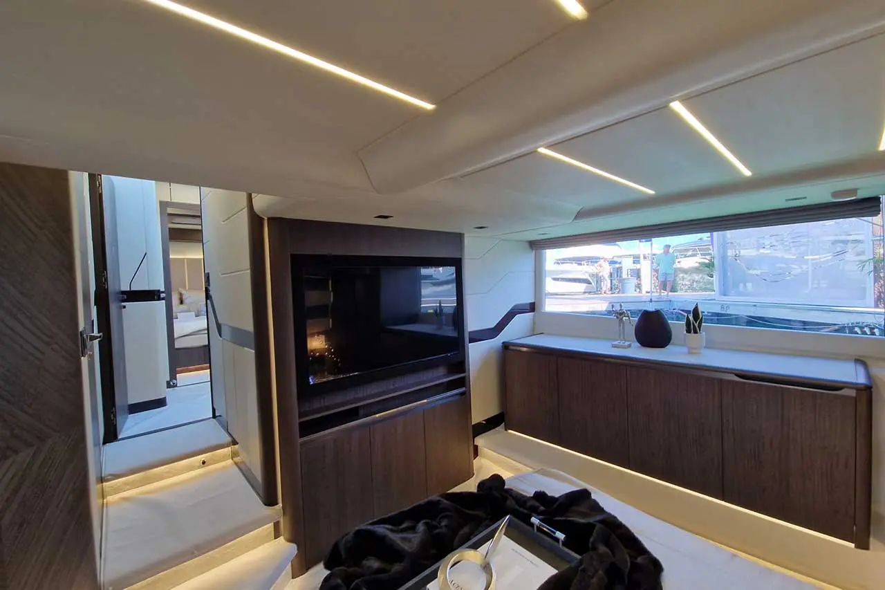 Luxurious yacht interior featuring a modern entertainment center, sleek cabinetry, and a large window with views of another yacht.