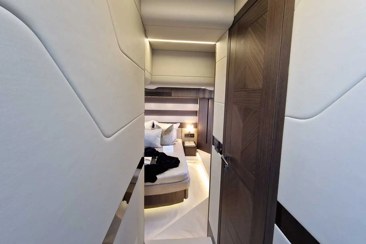 A modern yacht cabin hallway leads to a stylish bedroom with elegant lighting, soft textiles, and a cozy atmosphere.