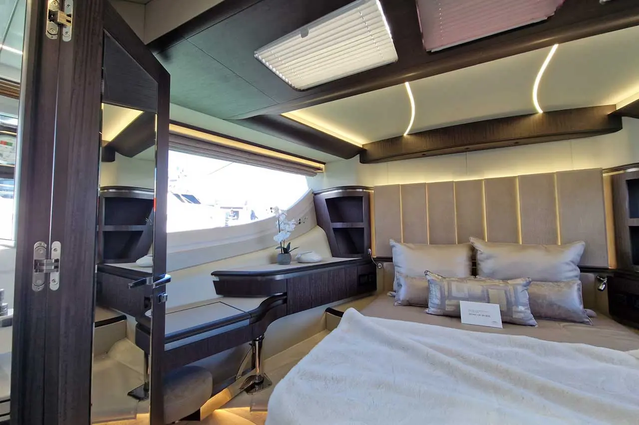 Luxurious yacht interior featuring a stylish bedroom with plush pillows, modern furnishings, and natural light from large windows.